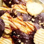 Chocolate-covered potato chips with caramel drizzle and crushed toppings on a plate.